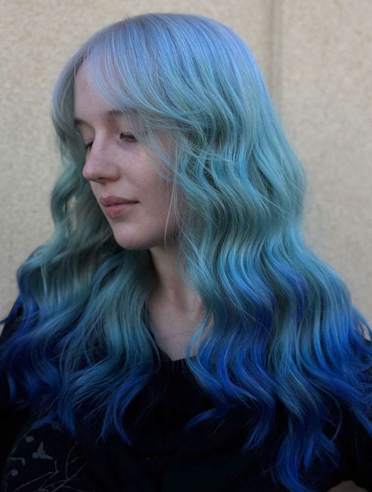 Woman with blue hair showcasing creative color services at Salon 730
