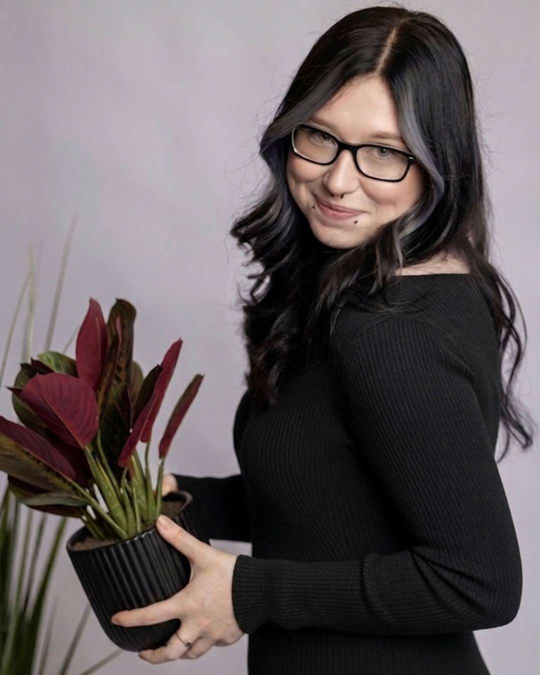 Vada, guest services team member at Salon 730 holding a plant
